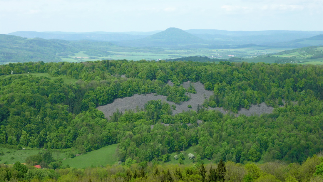 V popředí kamenné pole na Kamenné hůře (519 m) u Merboltic.