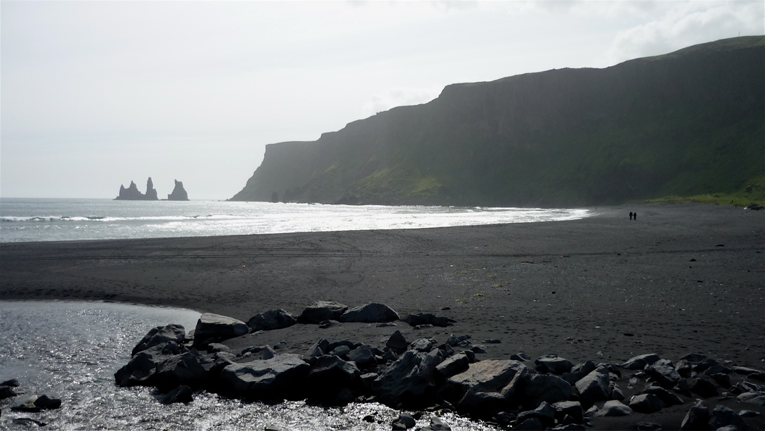 Černá bazaltová pláž a vzdálená skaliska Reynisdrangar.