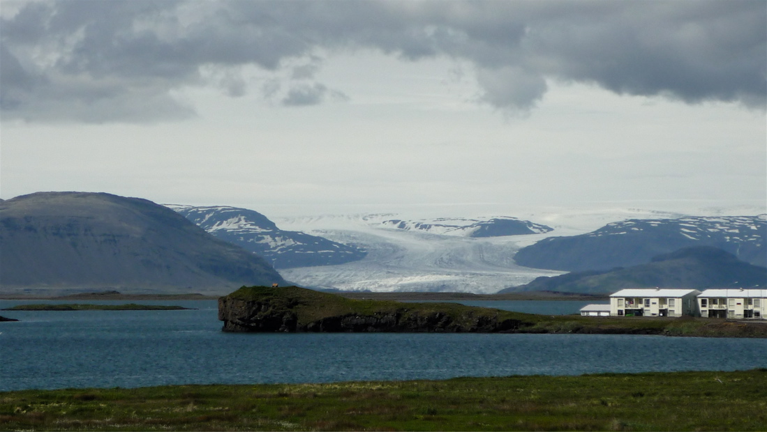 Bytovky a mohutný Vatnajökull za zátokou.